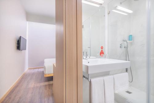 a white bathroom with a sink and a shower at Moov Hotel Évora in Évora
