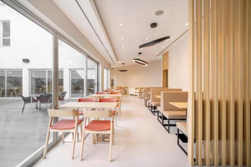 um restaurante com mesas e cadeiras e janelas grandes em Moov Hotel Évora em Évora