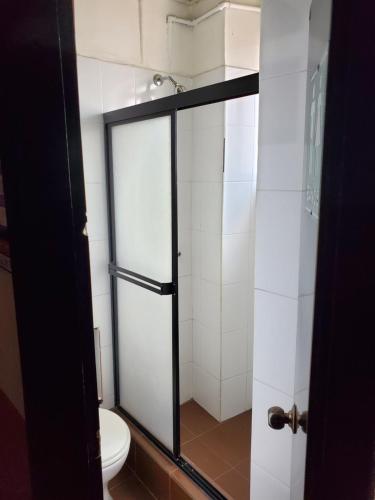 a bathroom with a toilet and a glass shower door at Hostal Juana de Arco in Quito
