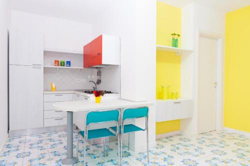 a kitchen with a table and two blue chairs at Settessenze Residence & Rooms in Agropoli