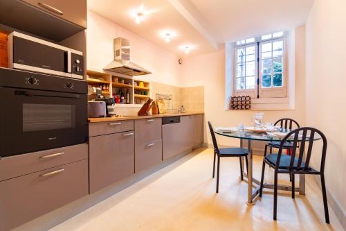 une cuisine avec une table, des chaises et une cuisinière dans l'établissement La petite conciеrgeriе du Grand-Rond, à Toulouse