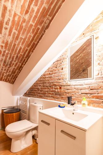 La salle de bains est pourvue de toilettes et d'un mur en briques. dans l'établissement La petite conciеrgeriе du Grand-Rond, à Toulouse