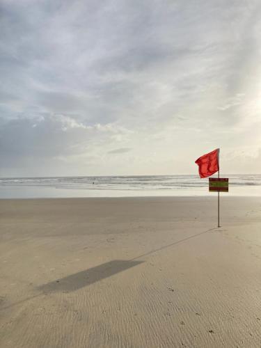 a red flag on a beach with the ocean at SPACELAND Mandrem in Mandrem