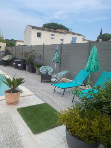 patio z niebieskimi krzesłami, parasolami i roślinami w obiekcie L'Hacienda, Haut de villa de deux chambres, avec salle de bain et toilettes WC privative w Fréjus