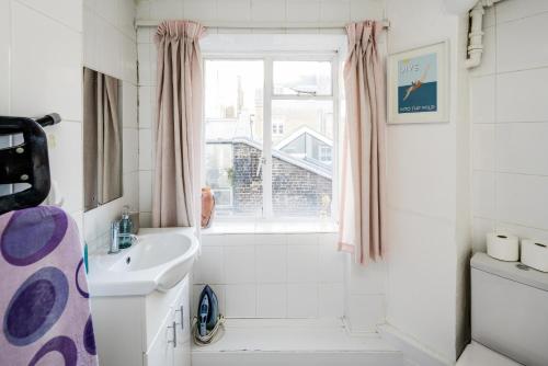 a white bathroom with a sink and a window at Affordable Flat in Fitzrovia in London