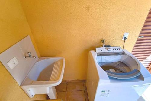 uma casa de banho com um WC branco e um lavatório. em Sobrado Com Piscina proximo aeroporto em Campo Grande