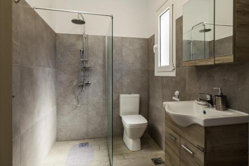 uma casa de banho com um chuveiro, um WC e um lavatório. em Manos House - Elegant Modern Escape em Svoronata