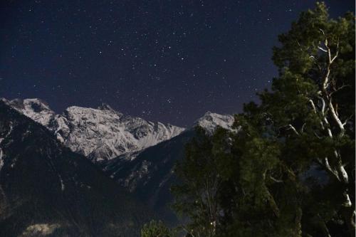a starry night with a snow covered mountain at Rudra homestays in Kalpa