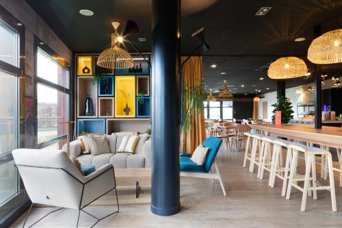 a restaurant with a bar with chairs and a table at ibis Douai Dechy in Dechy