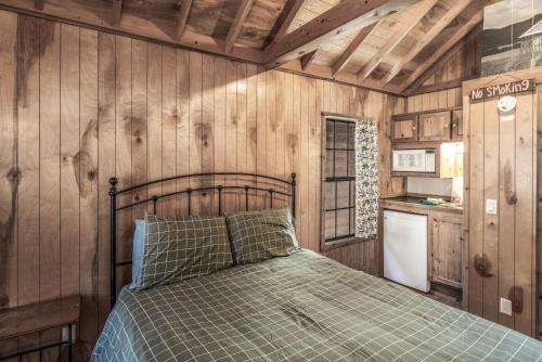 een slaapkamer met een bed in een kamer met houten wanden bij Rainbow Lake Cabin & RV Resort in Ruidoso