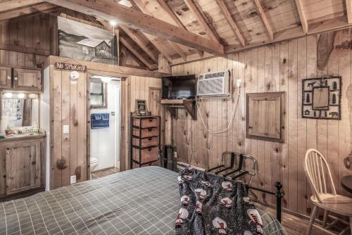 a bedroom with a bed in a room with wooden walls at Rainbow Lake Cabin & RV Resort in Ruidoso