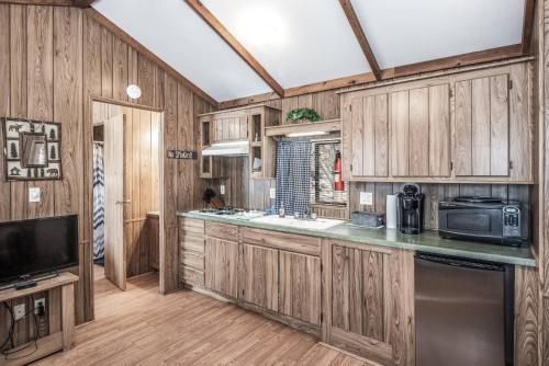 a kitchen with wooden cabinets and a microwave at Rainbow Lake Cabin & RV Resort in Ruidoso