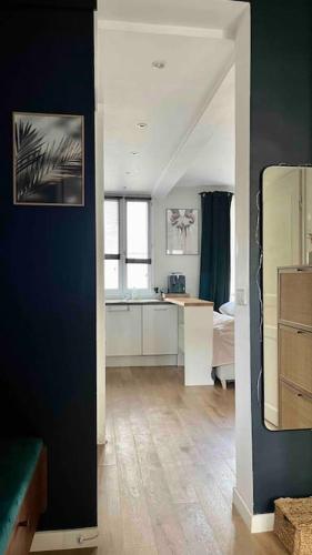 une cuisine avec des armoires blanches et un mur bleu dans l'établissement Appartement cozy pour découvrir Paris., à Issy-les-Moulineaux