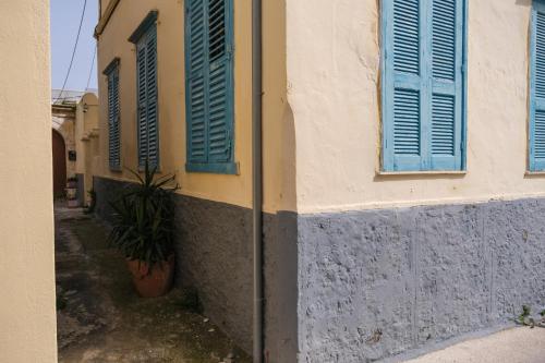 a building with blue shuttered windows and a potted plant at Archontiko Pataka in Rhodes Town