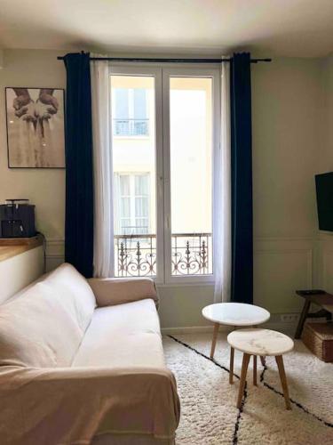 un salon avec un canapé et une fenêtre dans l'établissement Appartement cozy pour découvrir Paris., à Issy-les-Moulineaux