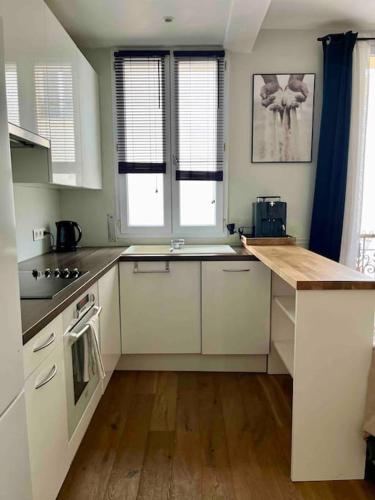 une cuisine avec des armoires blanches et un plancher en bois dans l'établissement Appartement cozy pour découvrir Paris., à Issy-les-Moulineaux