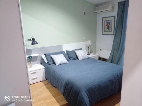 Schlafzimmer mit einem Bett mit blauer Bettwäsche und Kissen in der Unterkunft Apartamentos Casas Rurales "Paraje San Blas" in Alburquerque