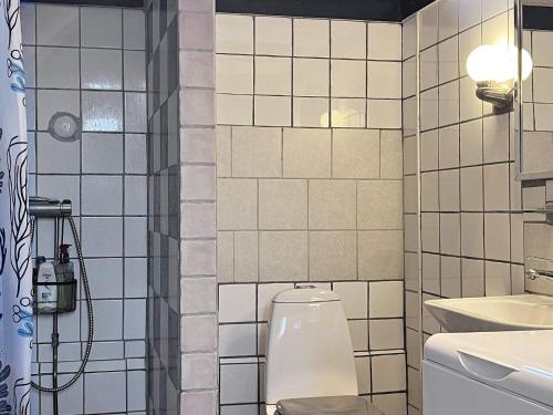 uma casa de banho em azulejos brancos com um WC e um chuveiro em Holiday home KLINTEHAMN IV em Klintehamn