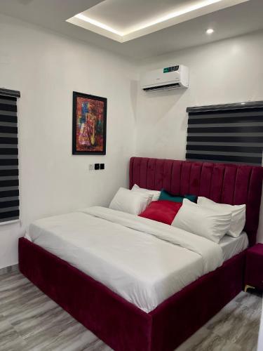 Cama grande en habitación con sofá rojo en Havmoorehomes Ltd en Port Harcourt