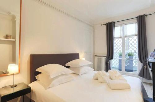 une chambre avec un lit blanc avec des oreillers blancs dans l'établissement Villa Eiffel, à Paris