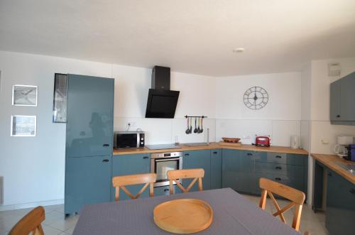 a kitchen with blue cabinets and a table and chairs at Appartement vue panoramique avec piscine pour 6 personnes &agrave; Nice quartier Pessicart in Nice
