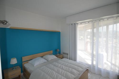 a bedroom with a large bed with a blue wall at Appartement vue panoramique avec piscine pour 6 personnes à Nice quartier Pessicart in Nice