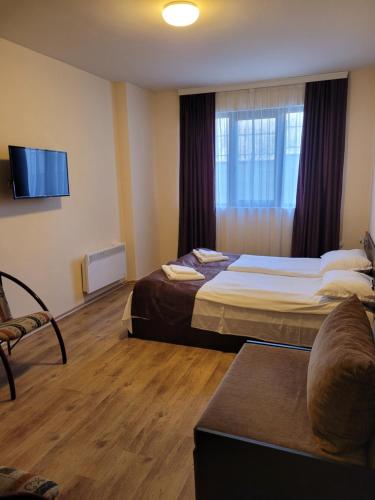 a hotel room with two beds and a flat screen tv at апартаменти Tryavna lake in Tryavna