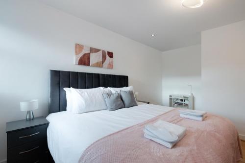 a bedroom with a large white bed with two towels on it at Modern Serviced One Bedroom Flat - Sleeps 4 - Near High Street & Train Station - CR5 London in Coulsdon