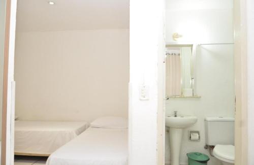 Baño blanco con cama y lavabo en Hotel Manoá Poa en Porto Alegre