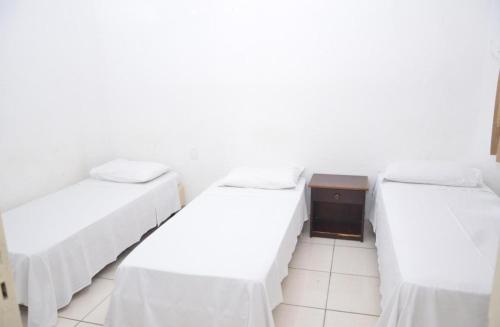 two beds in a room with white walls at Hotel Manoá Poa - Uma quadra do complexo da Santa Casa in Porto Alegre