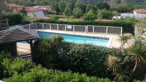 une piscine entourée d'une clôture blanche. dans l'établissement studio la colline bleue, à Biarritz