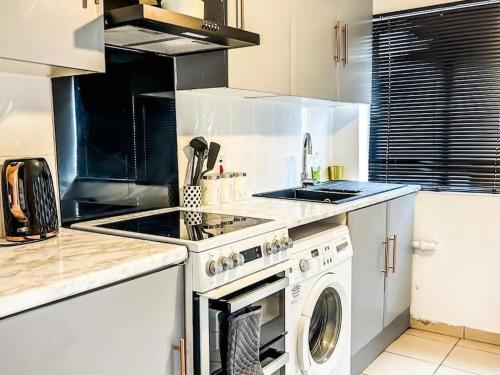 a kitchen with a stove and a washing machine at Spacious home with free parking in Shirley