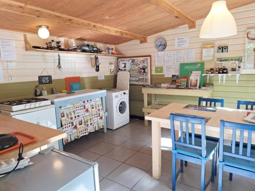 een keuken met tafels en stoelen en een wasmachine en droger bij Tenthutje BuitenWedde in Wedde