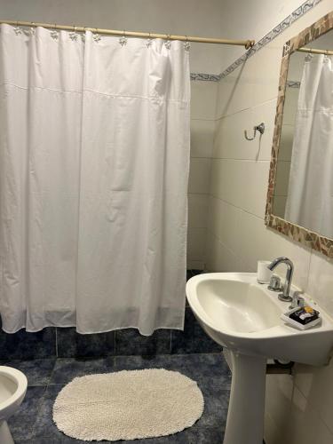 baño con cortina de ducha blanca y lavamanos en Ahicito - Casa en Tres Cerritos en Salta