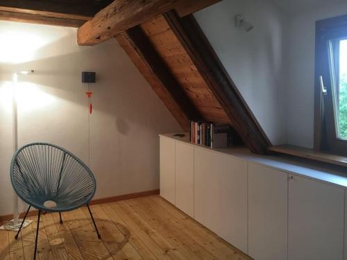 een kamer met een stoel en een raam op een zolder bij Gemütliches Maisonette-Studio in ehemaliger Scheune in Schwäbisch Gmünd