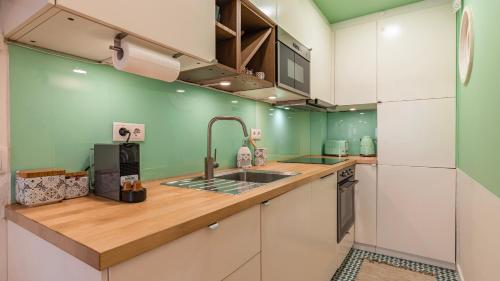 una cocina con armarios blancos y paredes verdes en M&M Home by LovelyStay en Lisboa