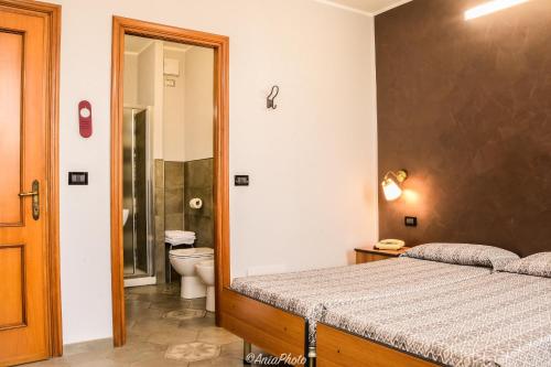 Albergo Florida Taggia في تاجيا: غرفة نوم بسرير وحمام مع مرحاض