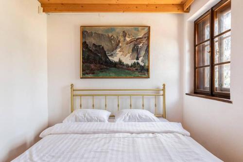 布萊德的住宿－Spacious And Historic Villa With Bled Castle View，卧室内的一张床铺,墙上有绘画作品
