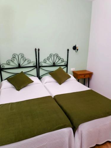 a bedroom with a large bed with green and white sheets at Complejo Godoy in Losar de la Vera