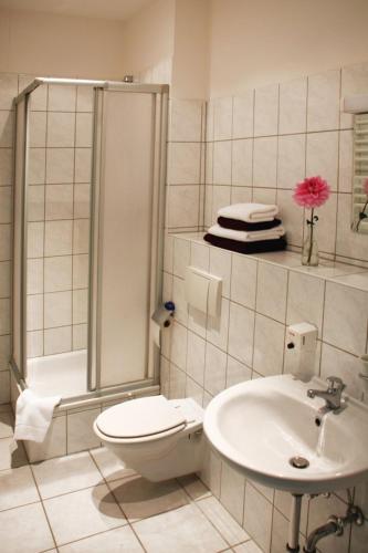 a bathroom with a toilet and a shower and a sink at Amarillo Hotel Velten in Velten