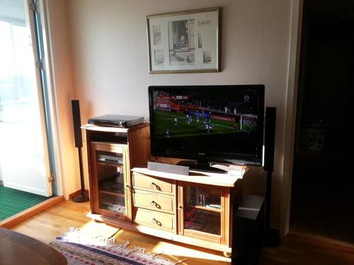 a flat screen tv sitting on a wooden entertainment center at Nära Friends Arena in Stockholm