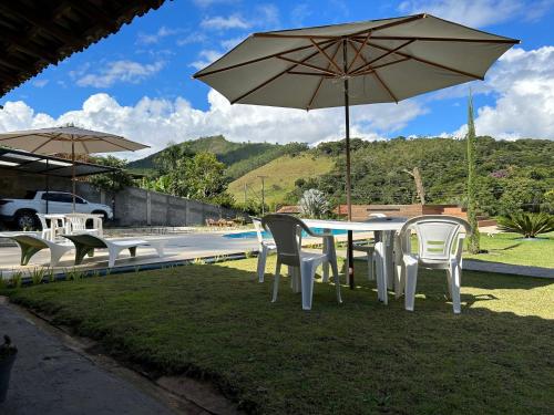 a table and chairs with an umbrella next to a pool at Sitio Real Cascata in Teresópolis