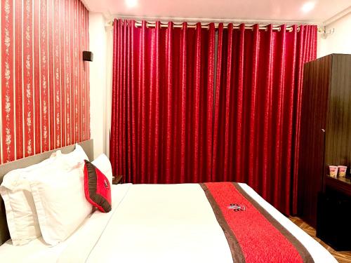 a bedroom with red drapes and a bed with white sheets at B.O.B Hotel in Cao Lãnh