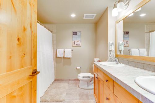 a bathroom with a toilet and a sink and a mirror at Whitefish Mountain Condo - Ski Resort On-Site! in Whitefish