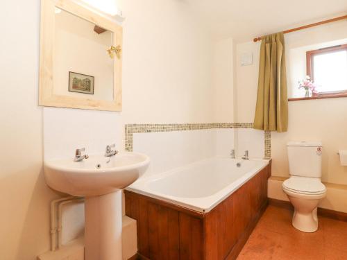 a bathroom with a sink and a tub and a toilet at Roofstones Cottage in Hawes