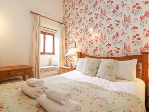a bedroom with a bed with a floral wallpaper at Roofstones Cottage in Hawes