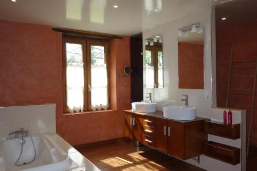 ein Badezimmer mit zwei Waschbecken, einer Badewanne und einem Spiegel in der Unterkunft Grand gite de la Bourrélie in Plazac