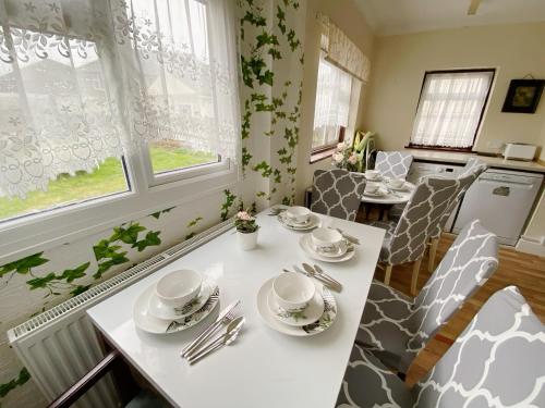 a kitchen with a white table with plates and silverware at Barking London House sleeps 12 - parking - train tube - airport in London