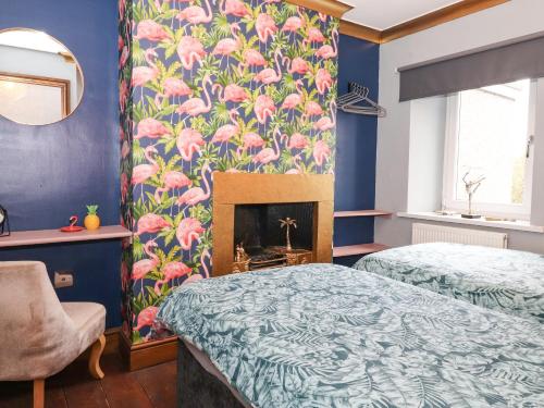 a bedroom with two beds and a fireplace at Flosh Cottage in Cleator