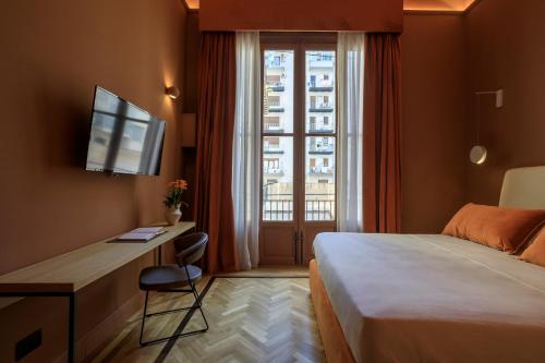 a hotel room with a bed and a desk and a window at Maison Belmonte - Suites in Palermo in Palermo